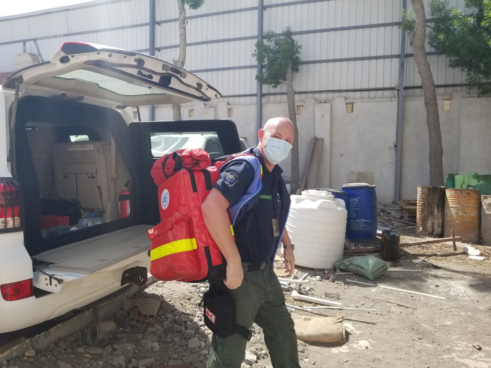 A paramedic preparing equipment beside an emergency response vehicle