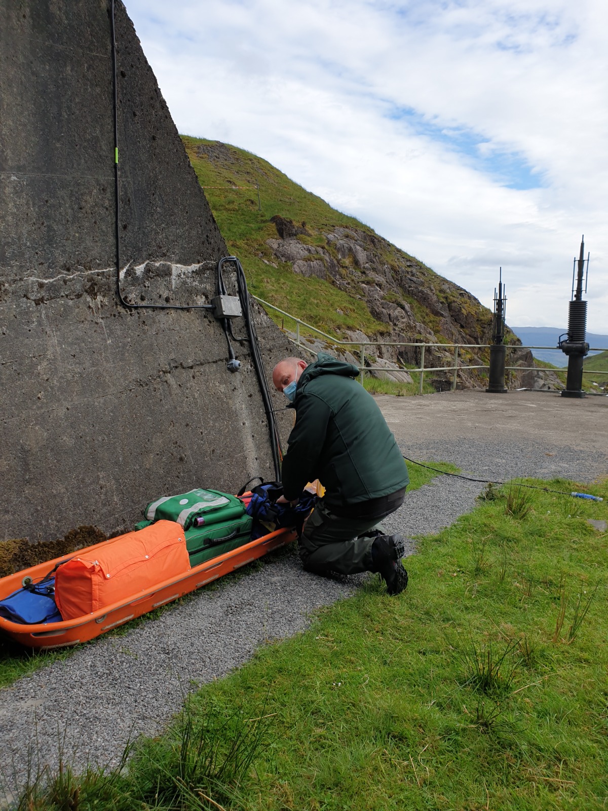 A medical professional preparing rescue equipment in a remote coastal setting